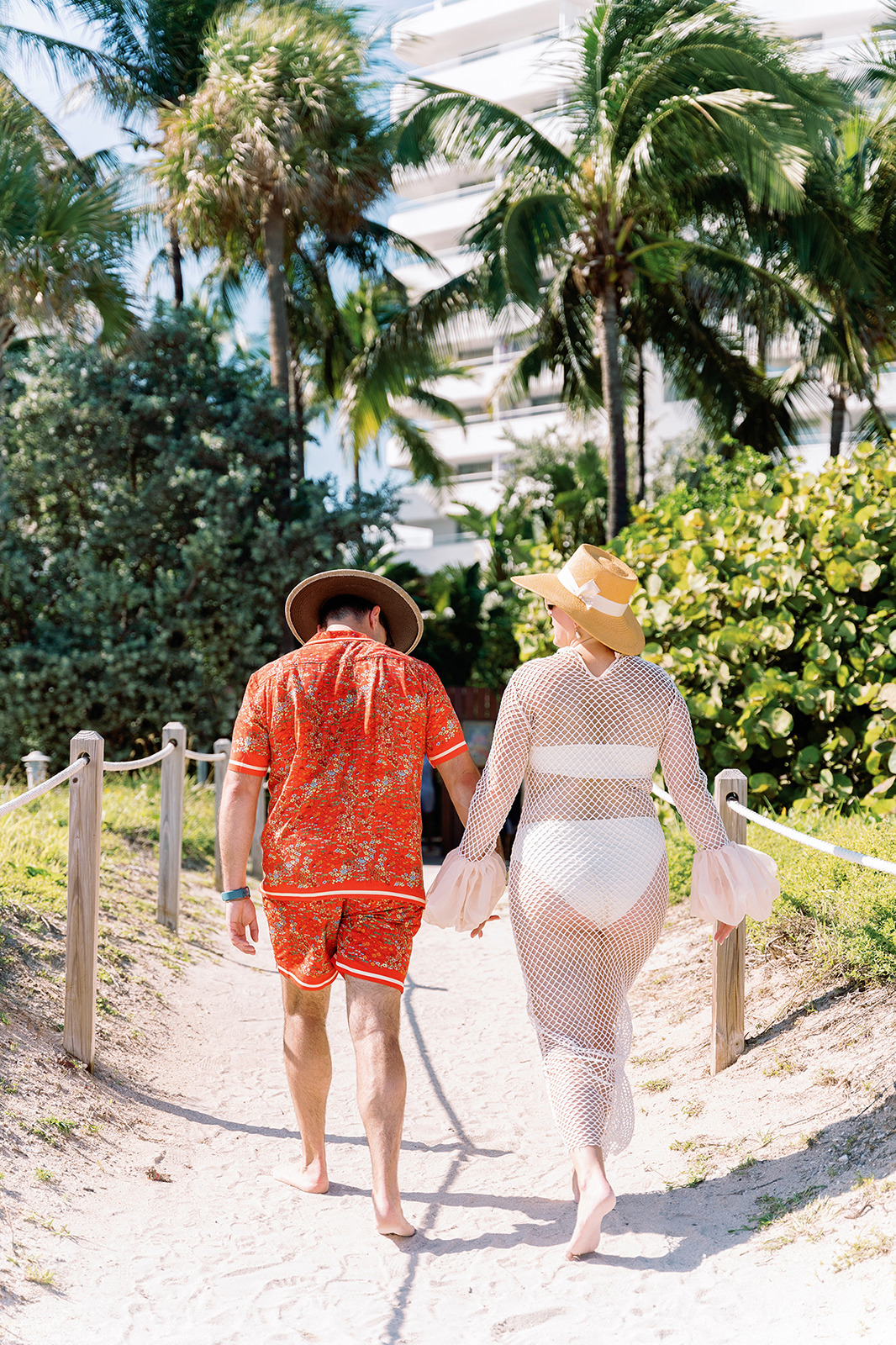 Couple walking hand in hand toward the beach during a Faena wedding weekend