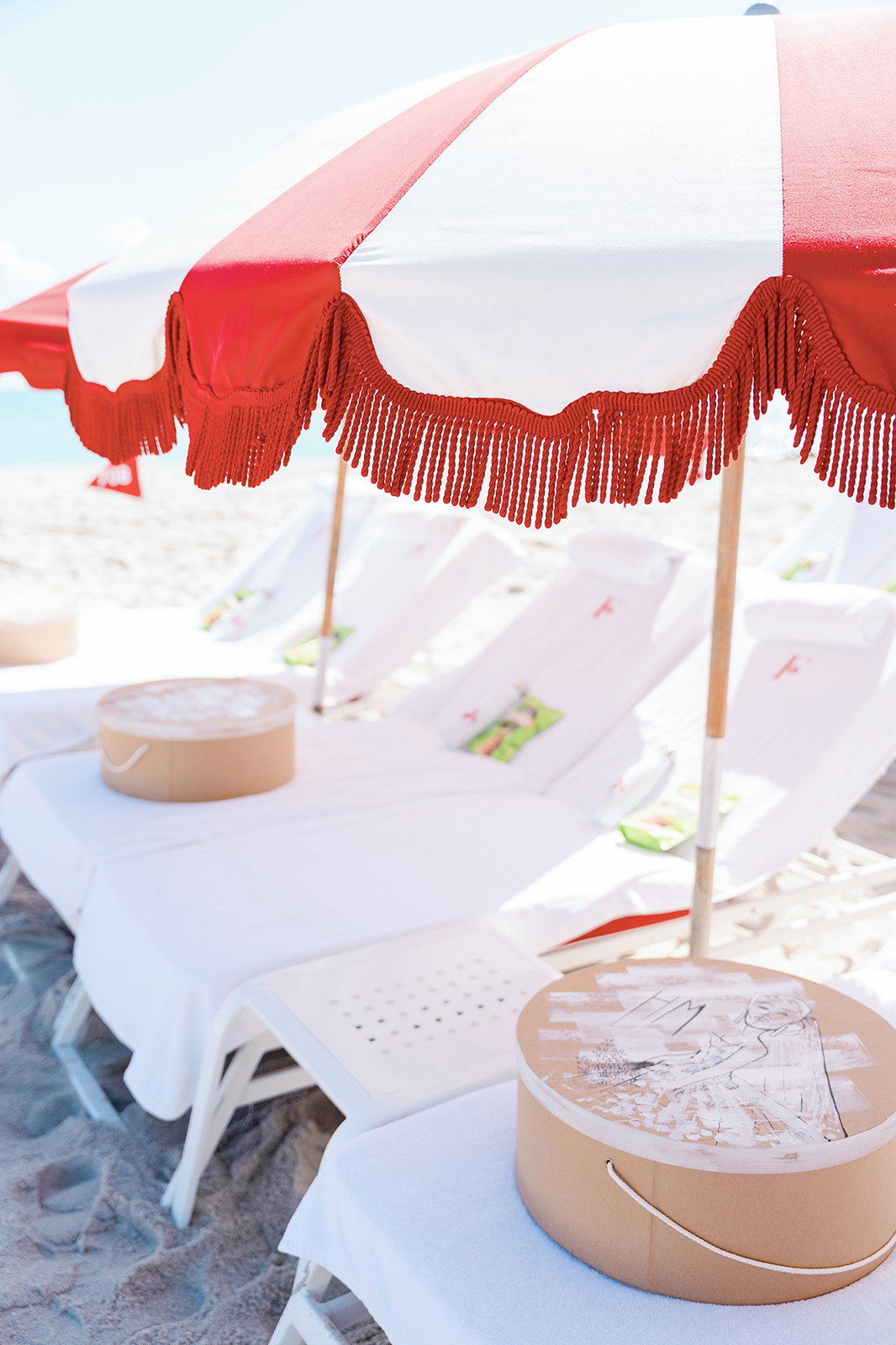 Red and white Faena Beach umbrellas and lounge chairs set for a Miami Beach wedding weekend celebration