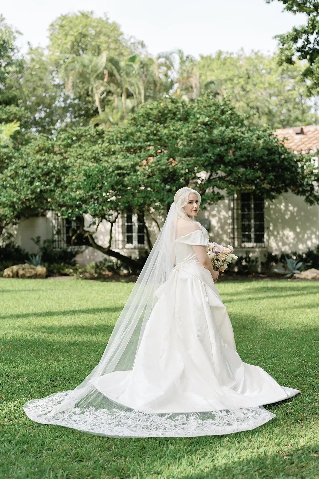Bride in an off-the-shoulder wedding gown with cathedral veil during a Fisher Island wedding portrait