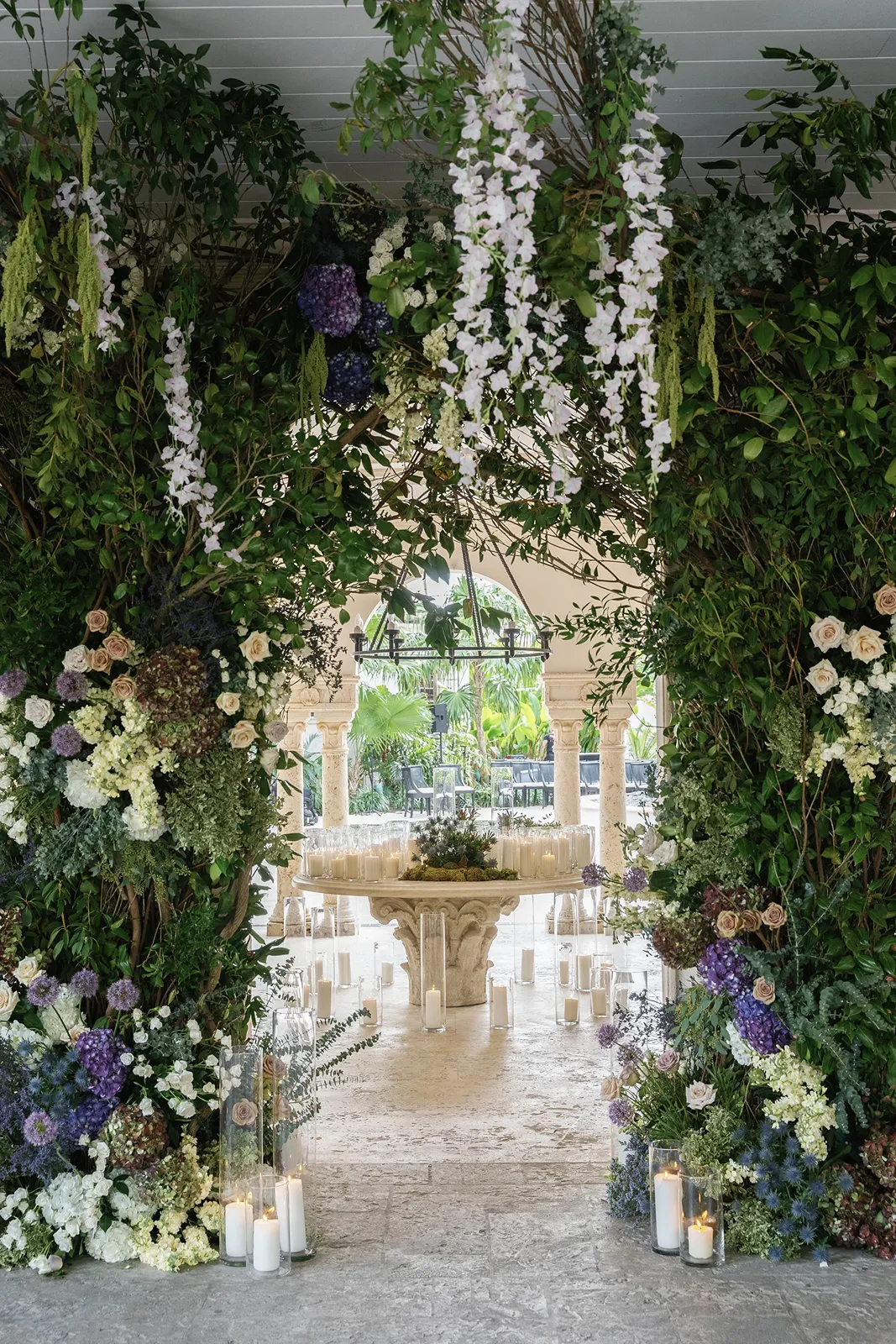 Lush floral ceremony arch with candles at a Fisher Island wedding ceremony