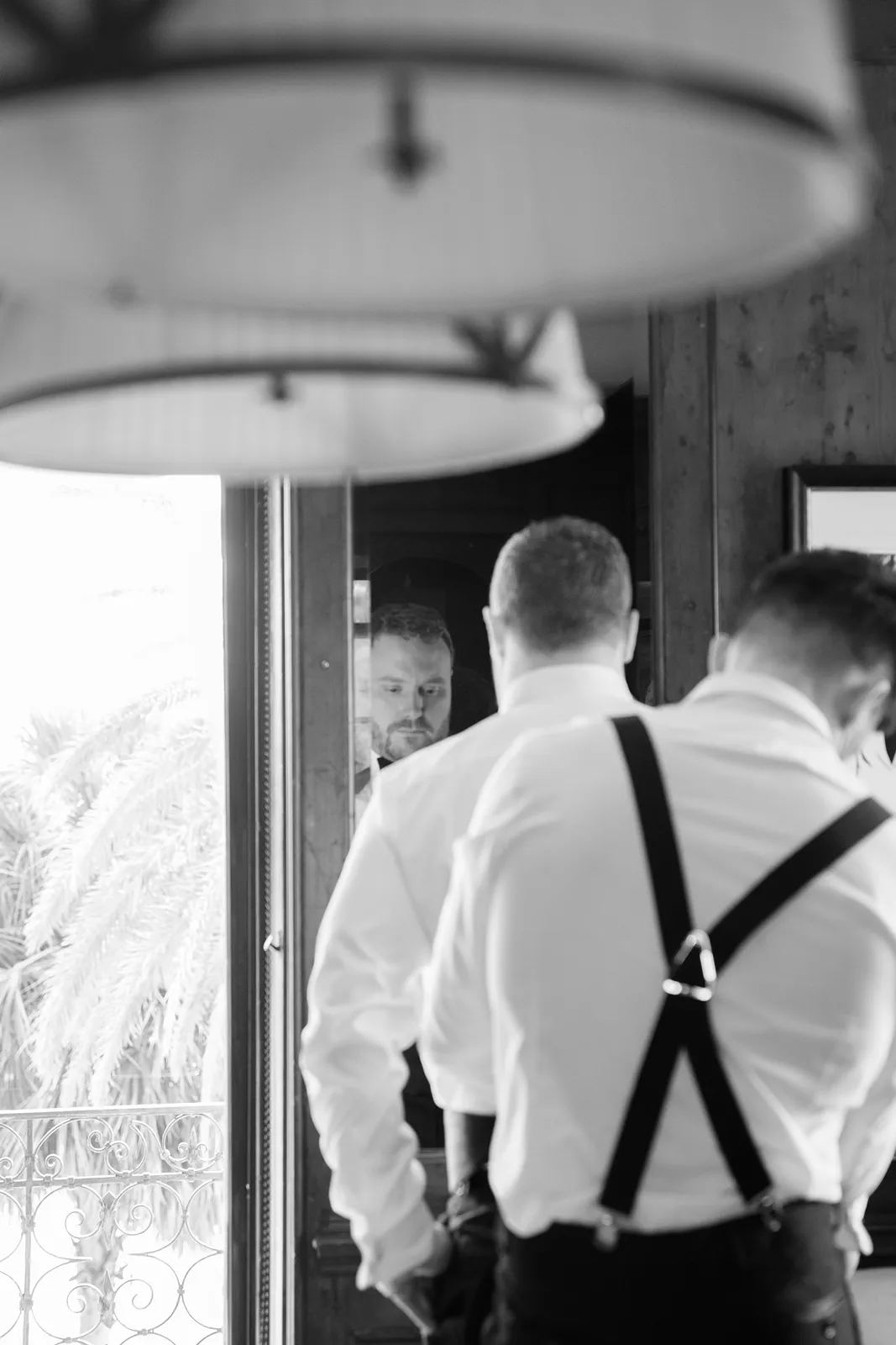 Black and white photo of the groom getting ready in a Fisher Island estate, adjusting his shirt before the wedding ceremony.