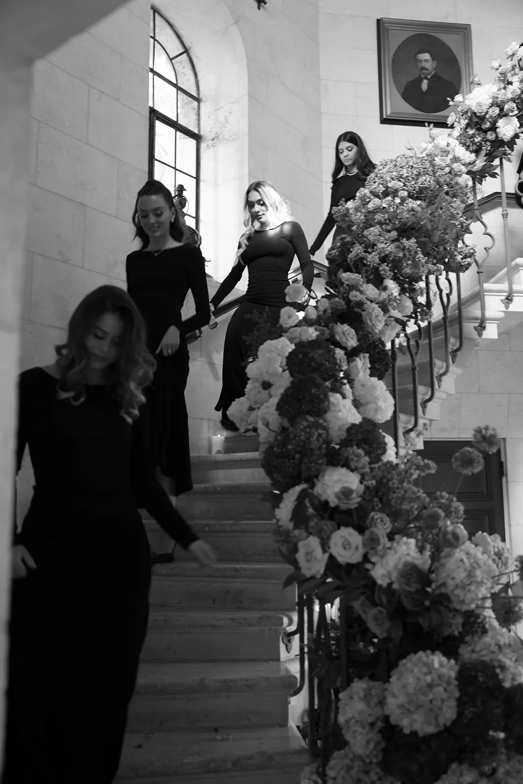 Bridesmaids descending a grand staircase with floral installation at a Fisher Island wedding venue