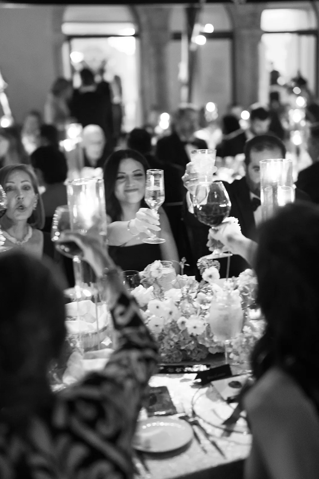 Black and white wedding reception toast with guests raising glasses at an elegant Fisher Island wedding dinner