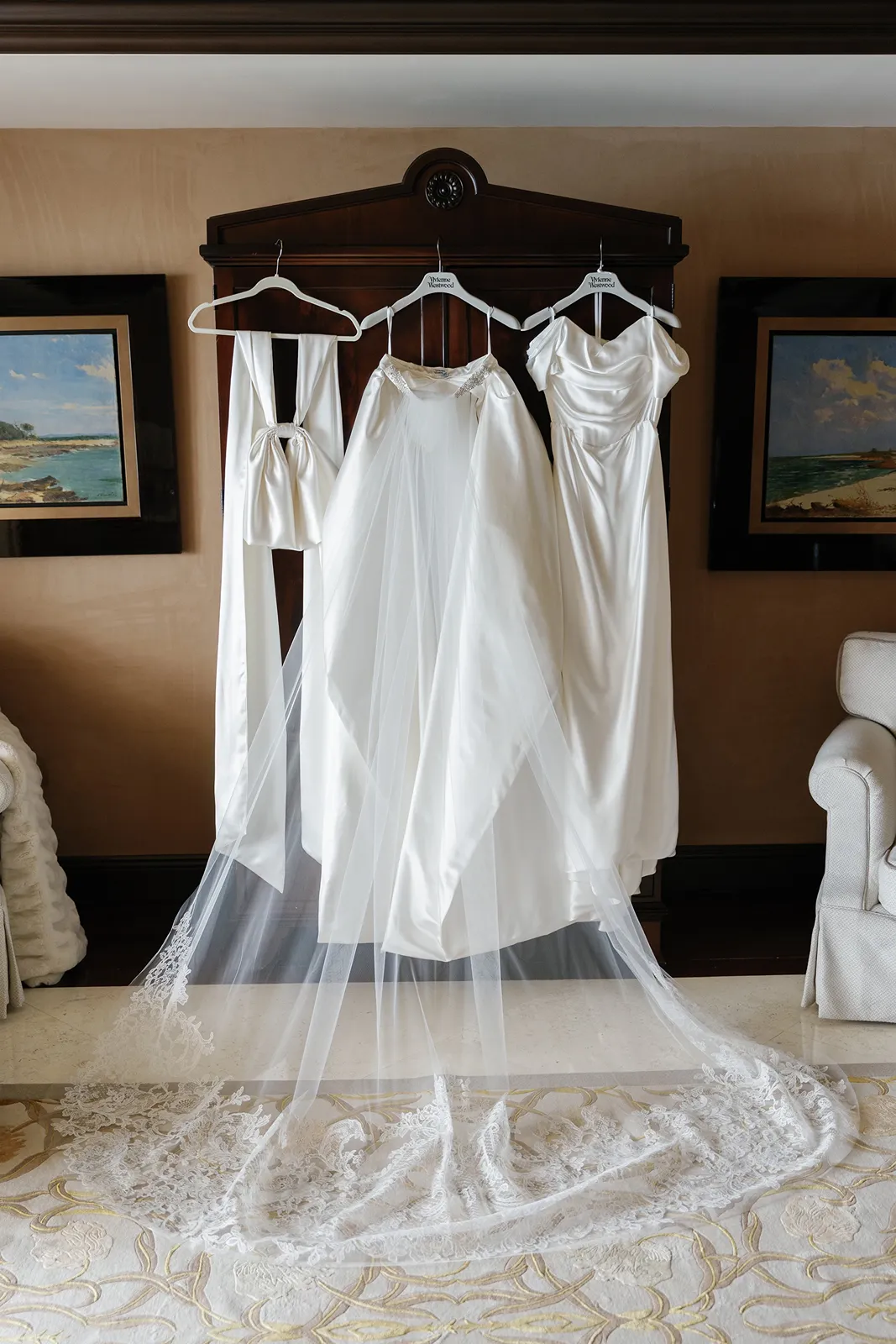 Bride’s wedding dress, veil, and reception outfit hanging in a luxury suite before a Fisher Island wedding