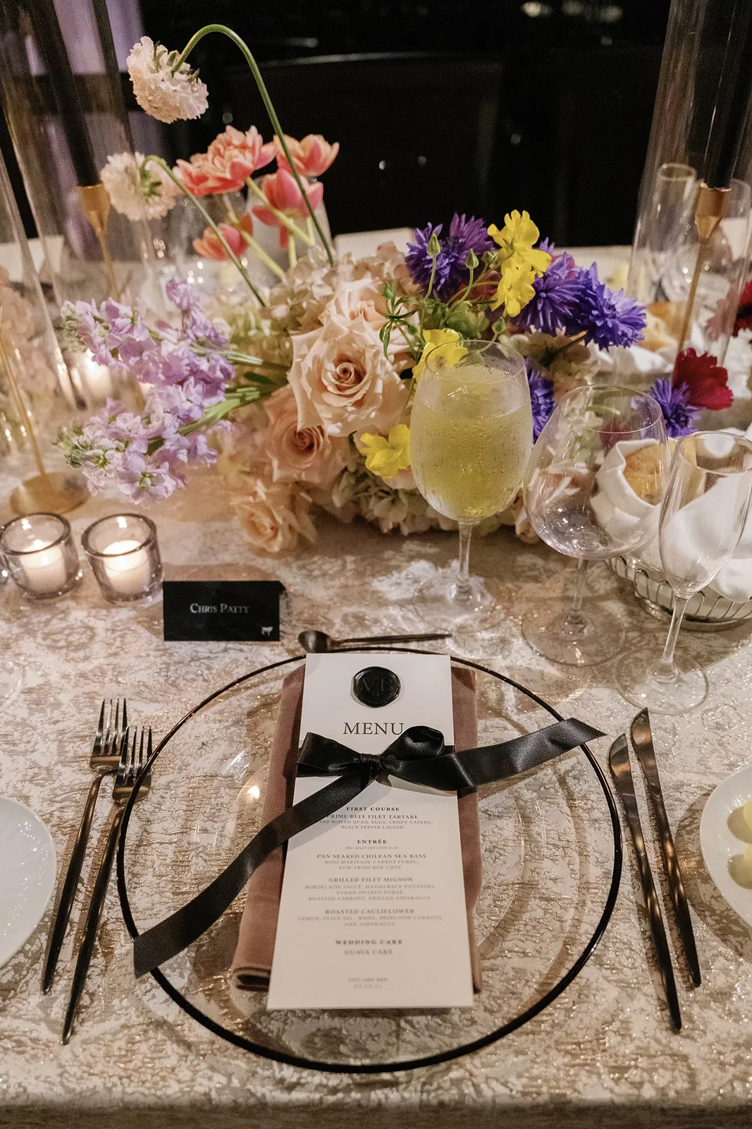 Elegant Fisher Island wedding reception table with colorful floral centerpiece, candlelight, and custom menu card at the place setting