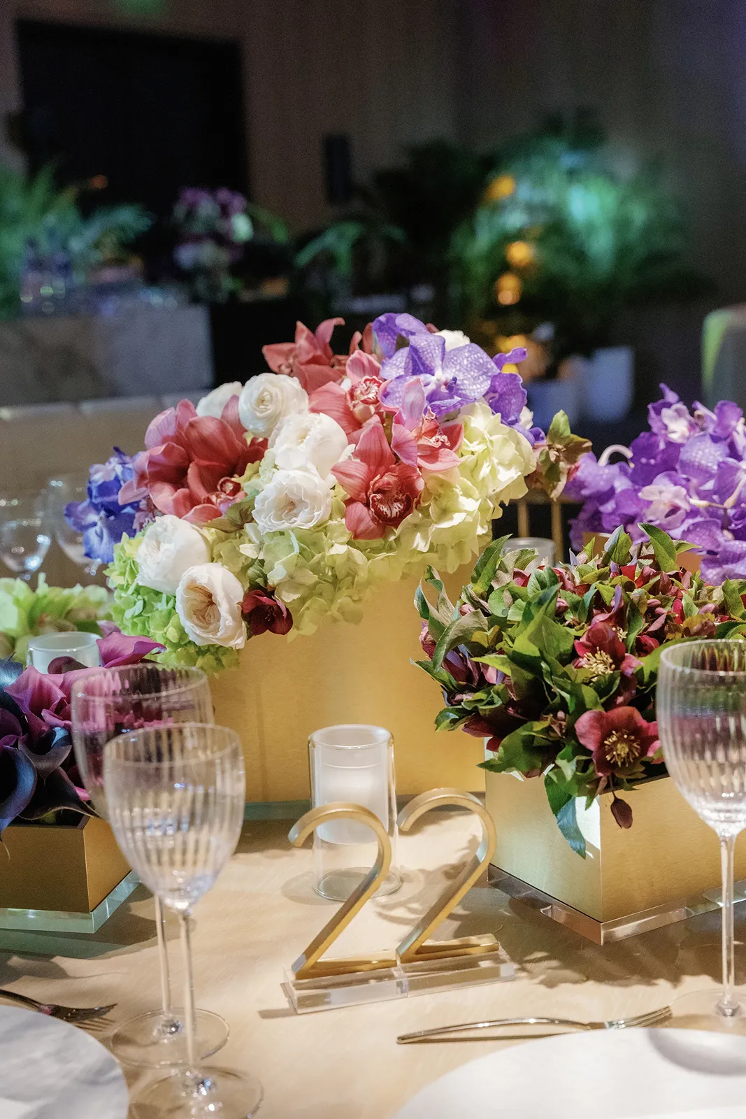 Colorful wedding floral arrangements with roses and orchids on reception tables at the Miami Beach EDITION