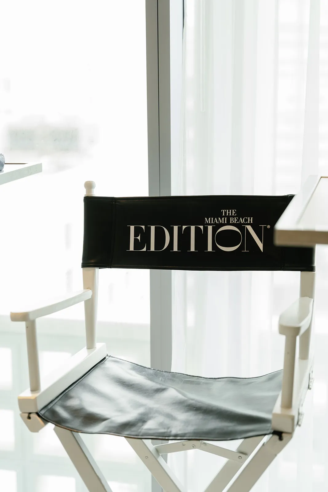 Black director-style chair with white lettering placed near a window during wedding preparations
