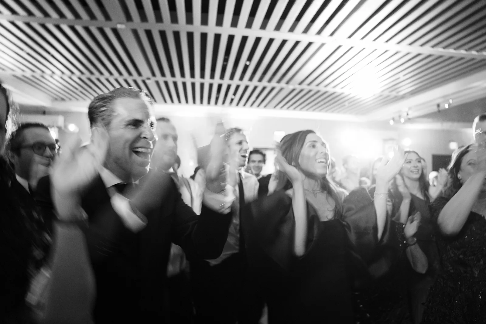 Wedding guests clapping and cheering together on the dance floor during the celebration