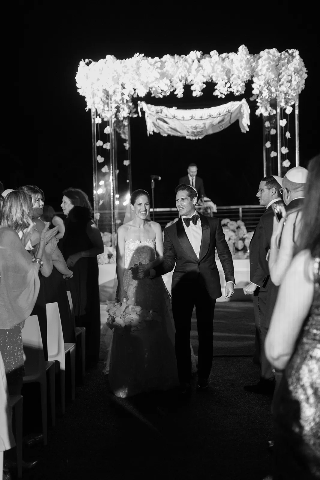 Bride and groom walking back up the aisle beneath a floral chuppah during their Miami Beach EDITION wedding ceremony