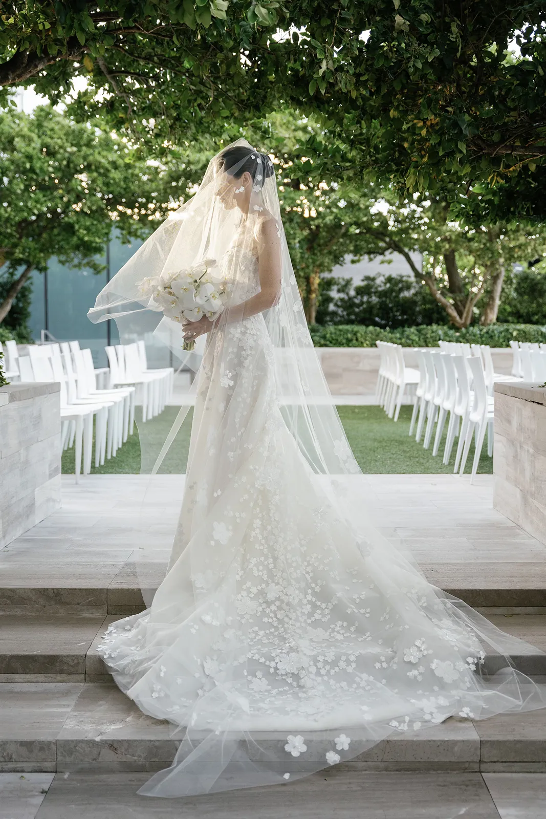 Bride walking down the aisle holding a white orchid bouquet during an outdoor ceremony at the Miami Beach EDITION