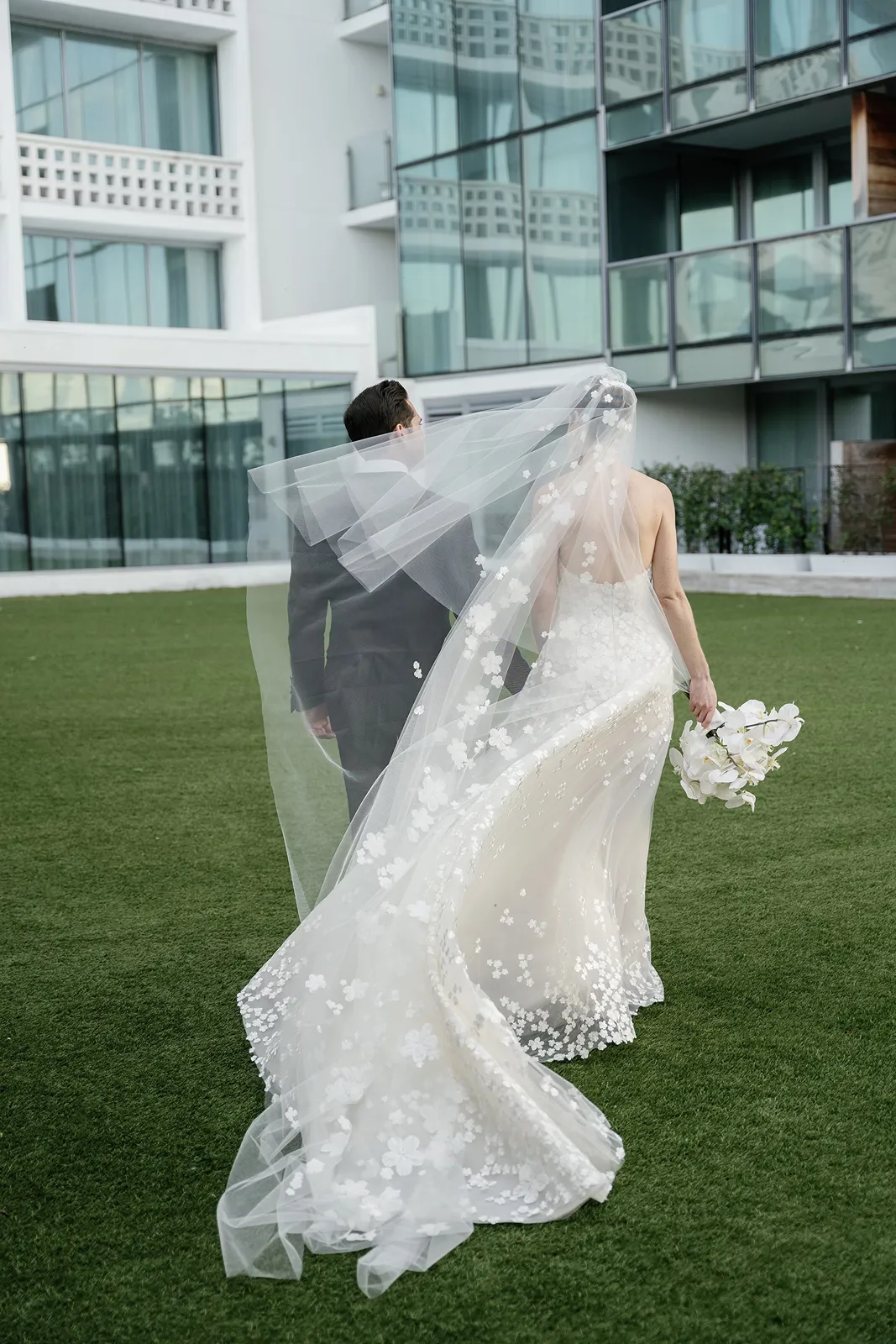 Bride and groom walking hand in hand as the bride’s veil flows behind them during their Miami Beach EDITION wedding