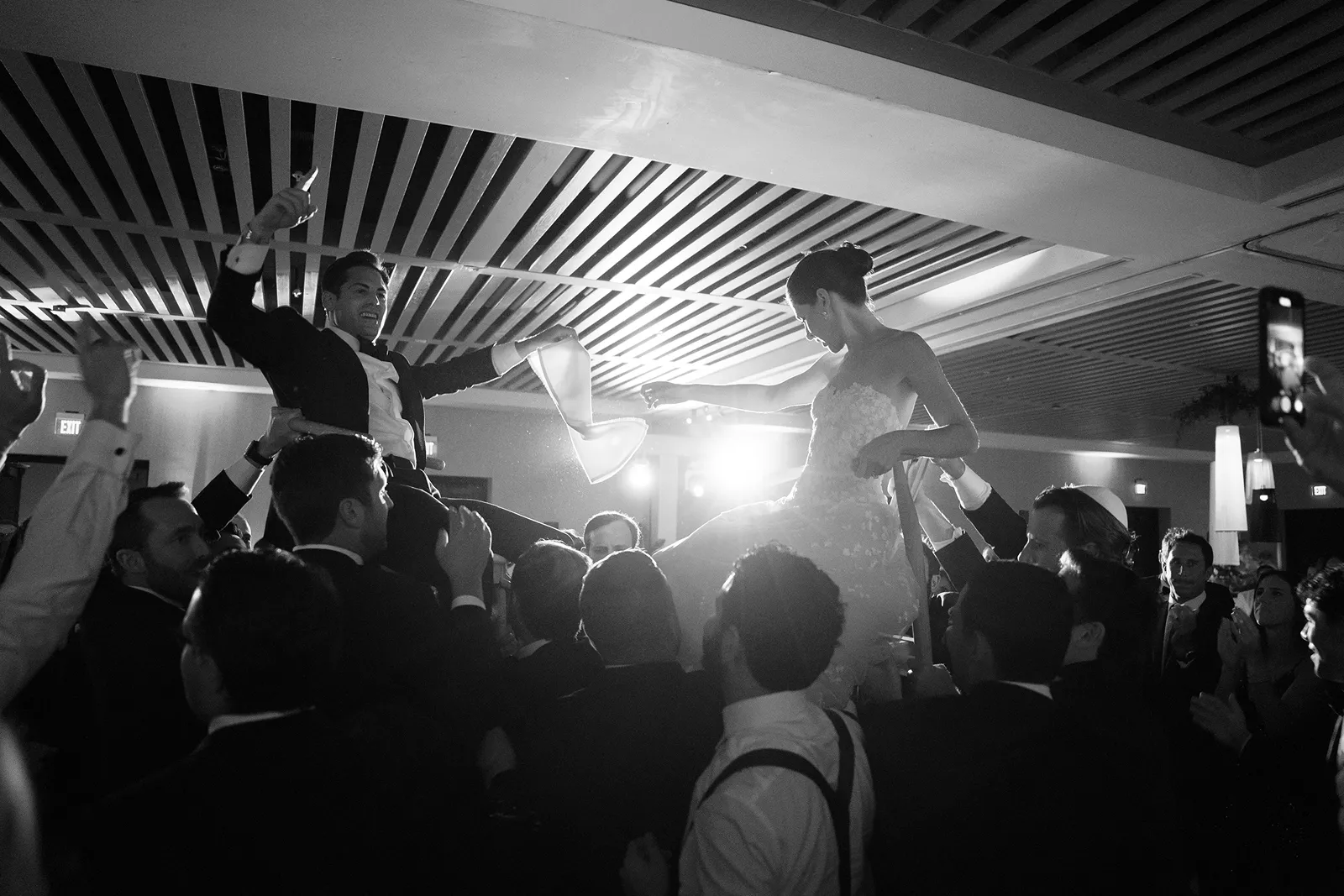 Bride and groom lifted in the air during the hora celebration at a Miami Beach EDITION wedding reception