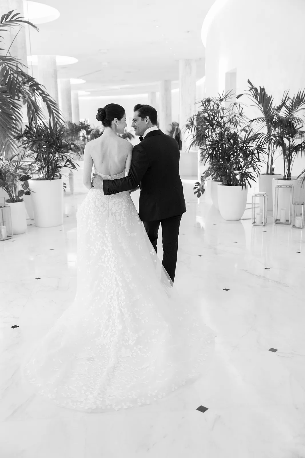 Bride and groom walking arm in arm through the bright, modern lobby of the Miami Beach EDITION