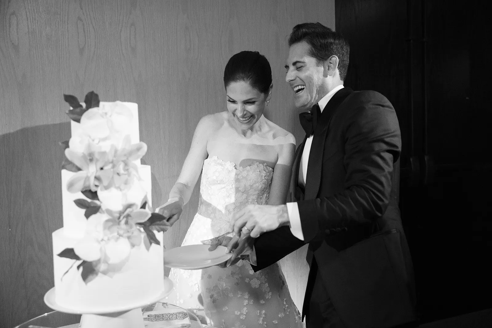 Bride and groom laughing while cutting their wedding cake during reception at the Miami Beach EDITION