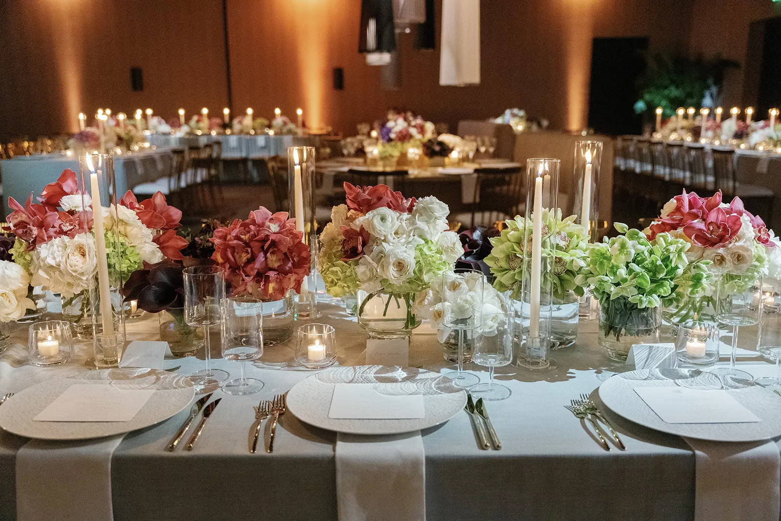 Wedding reception table styled with candlelight, pastel floral centerpieces, and place settings