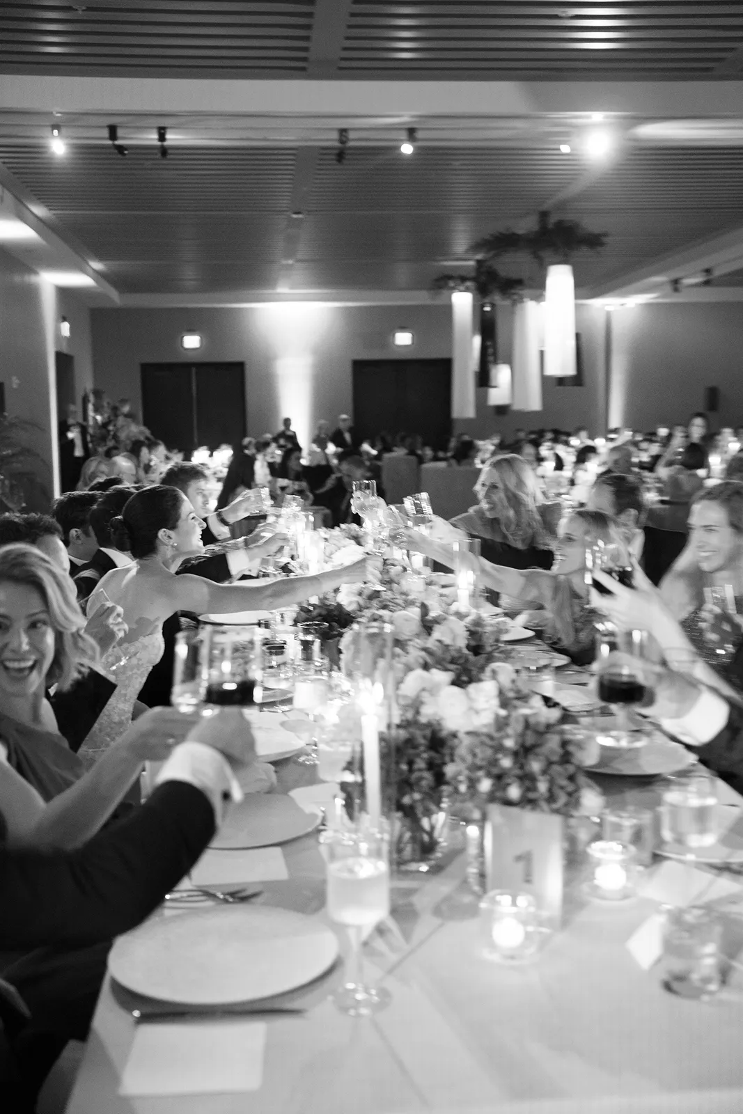 Wedding guests raising glasses in a joyful toast during an elegant candlelit dinner
