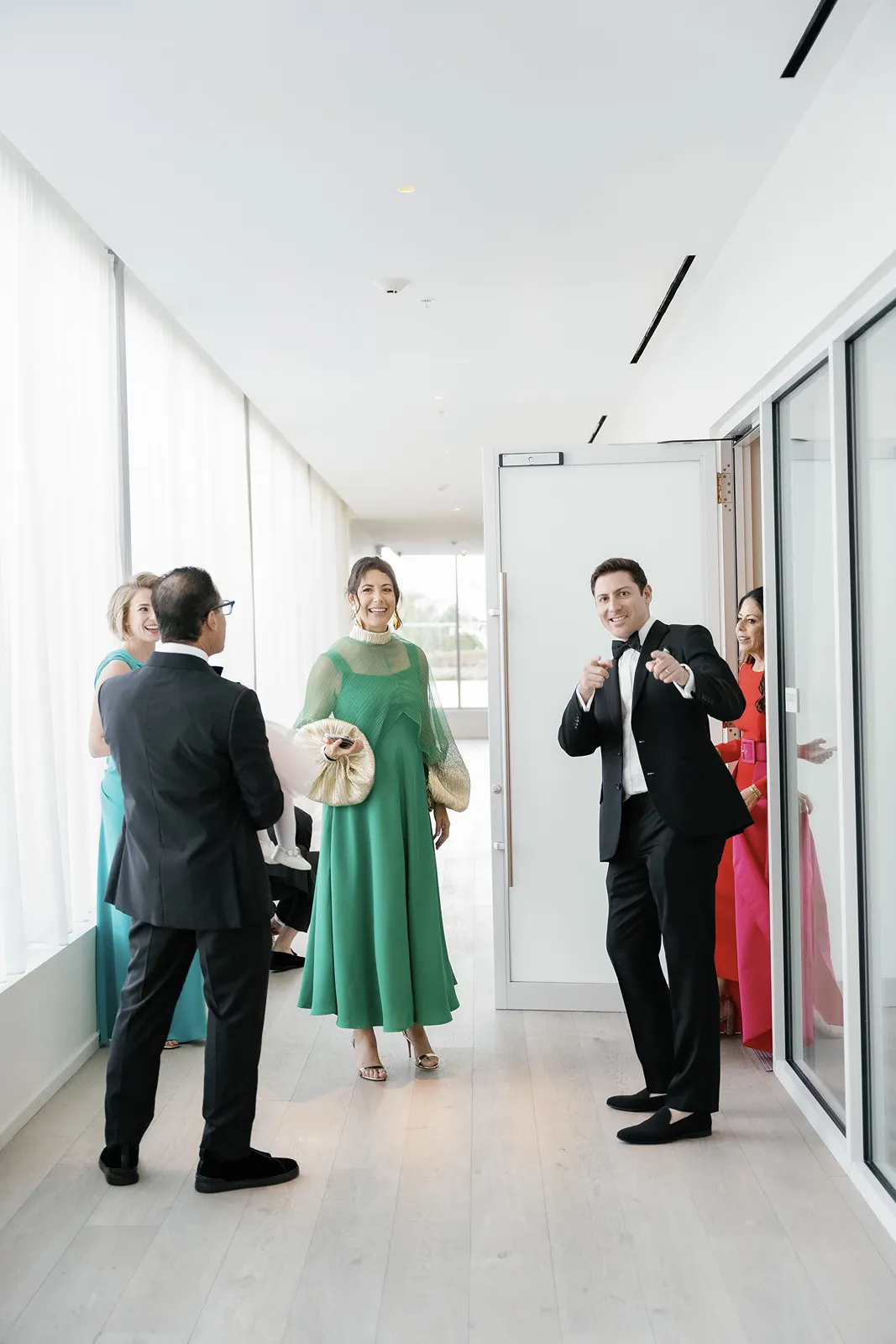 Wedding party standing together in a bright hallway sharing a relaxed moment before the ceremony