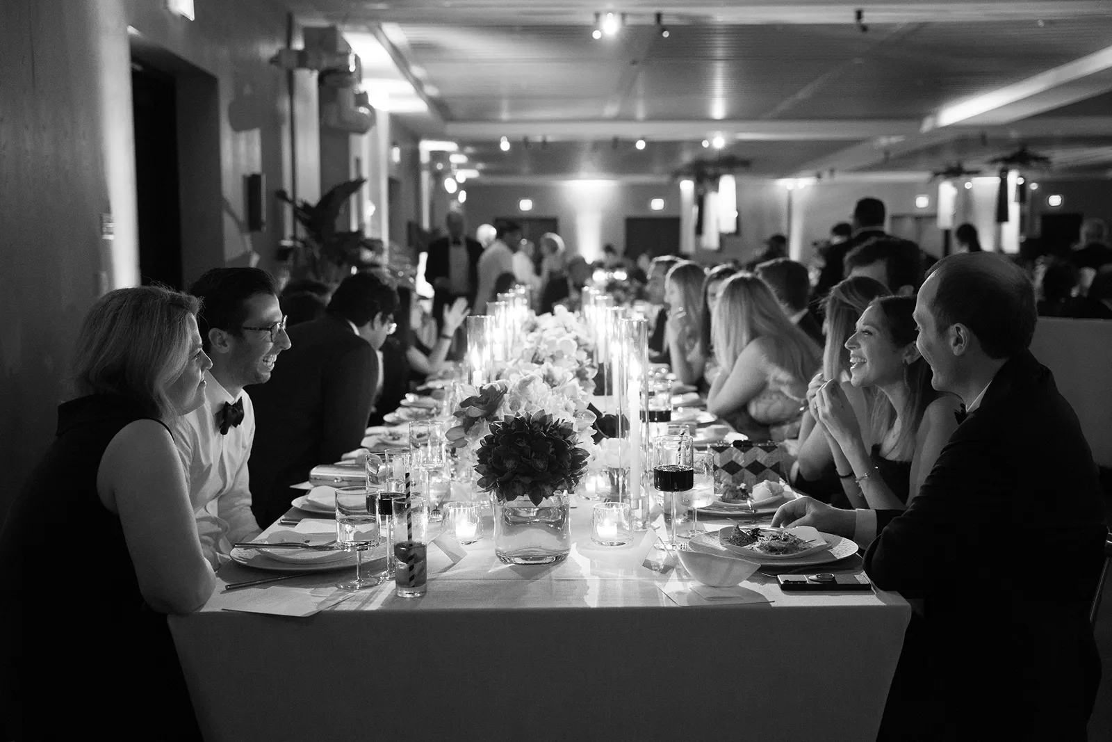 Wedding guests laughing and talking during a lively candlelit dinner reception