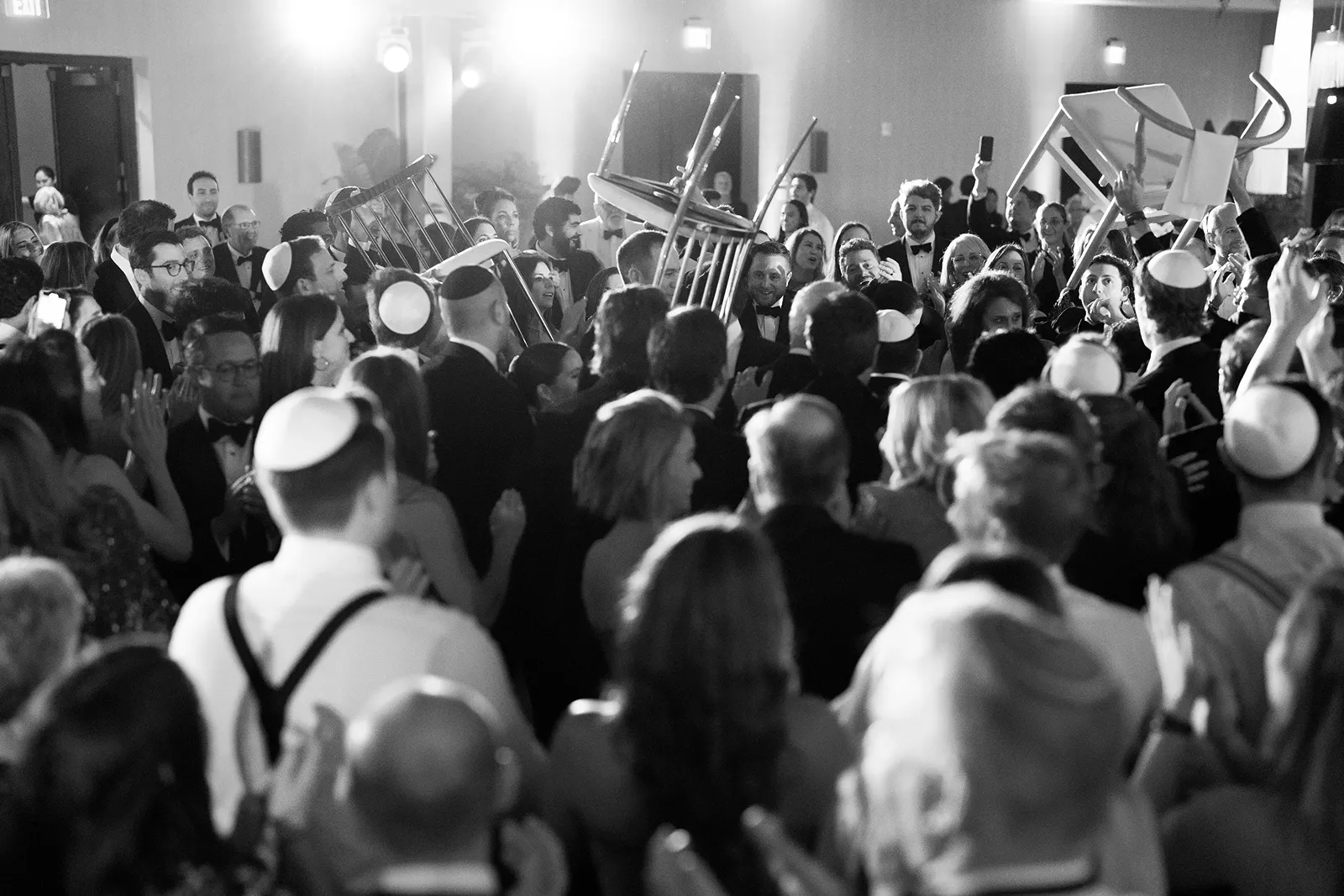 Energetic hora dance with guests lifted on chairs during reception