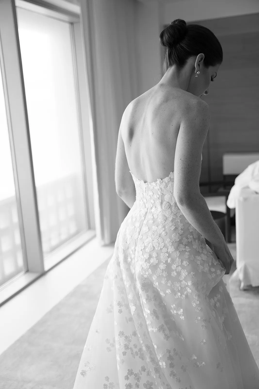Bride seen from behind adjusting her lace wedding gown during quiet getting ready moments