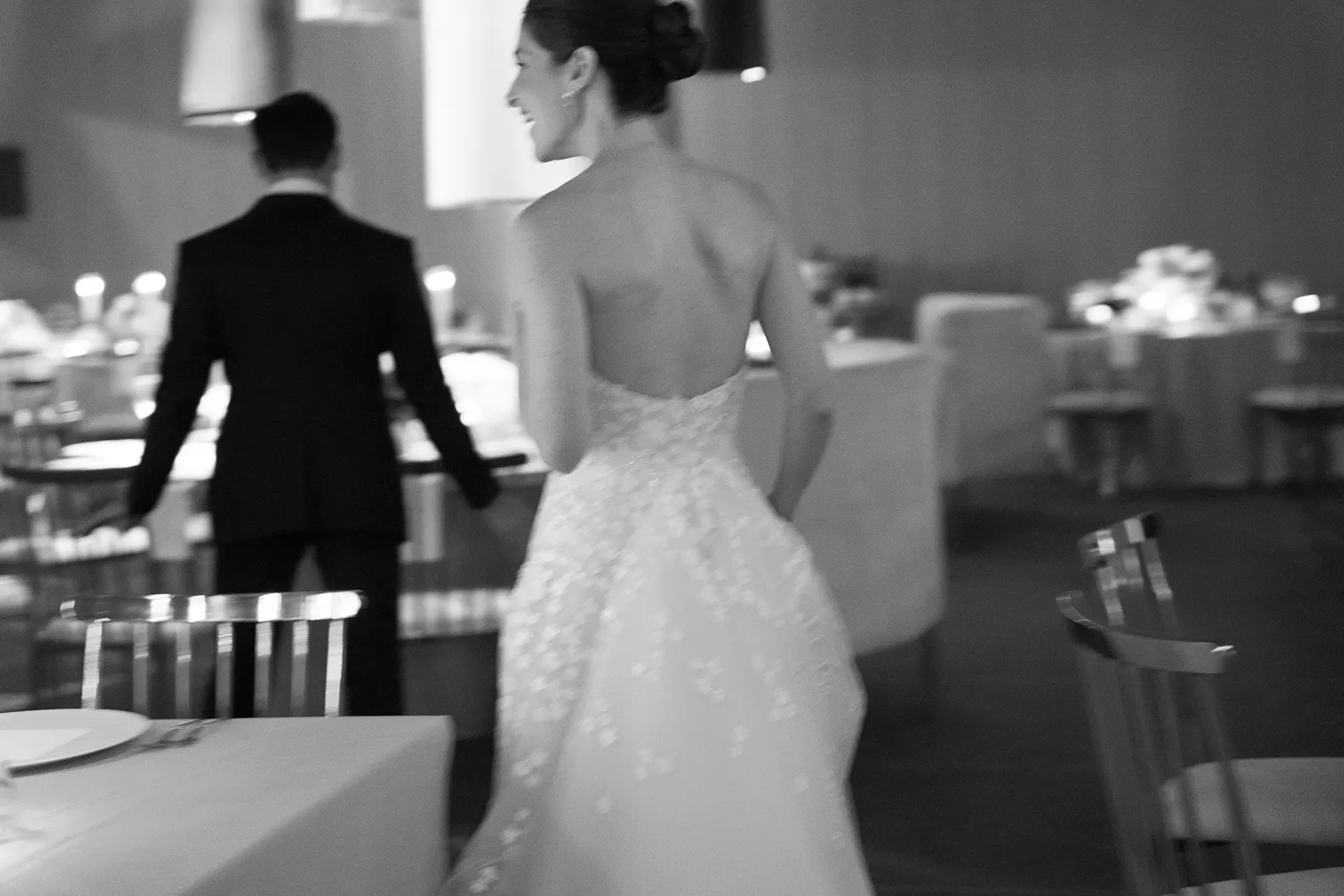 Wedding reception table styled with tall candles, glassware, and colorful floral centerpieces