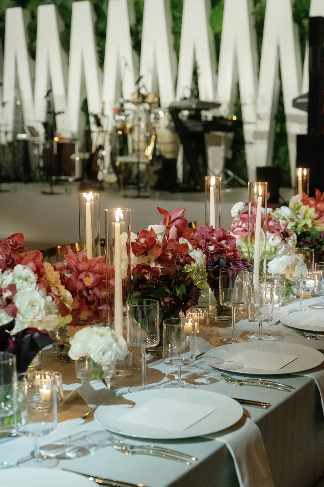 Bride and groom standing together holding hands for a bright, elegant wedding portrait surrounded by greenery