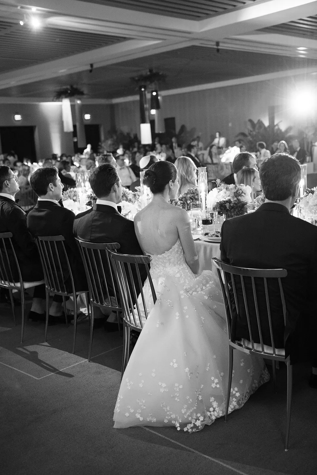 Bride seated at the head table alongside family members during the wedding reception dinner