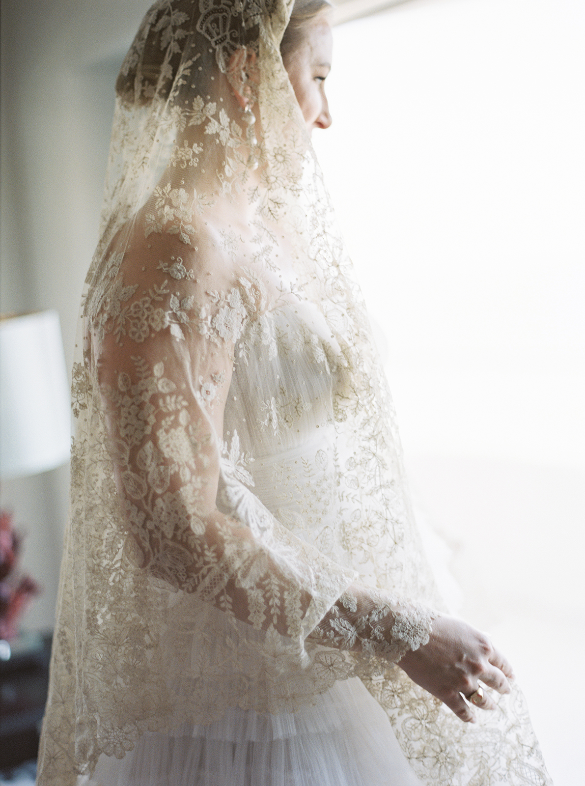 bride overlooking window as she wears her great grandmother's veil as an heirloom