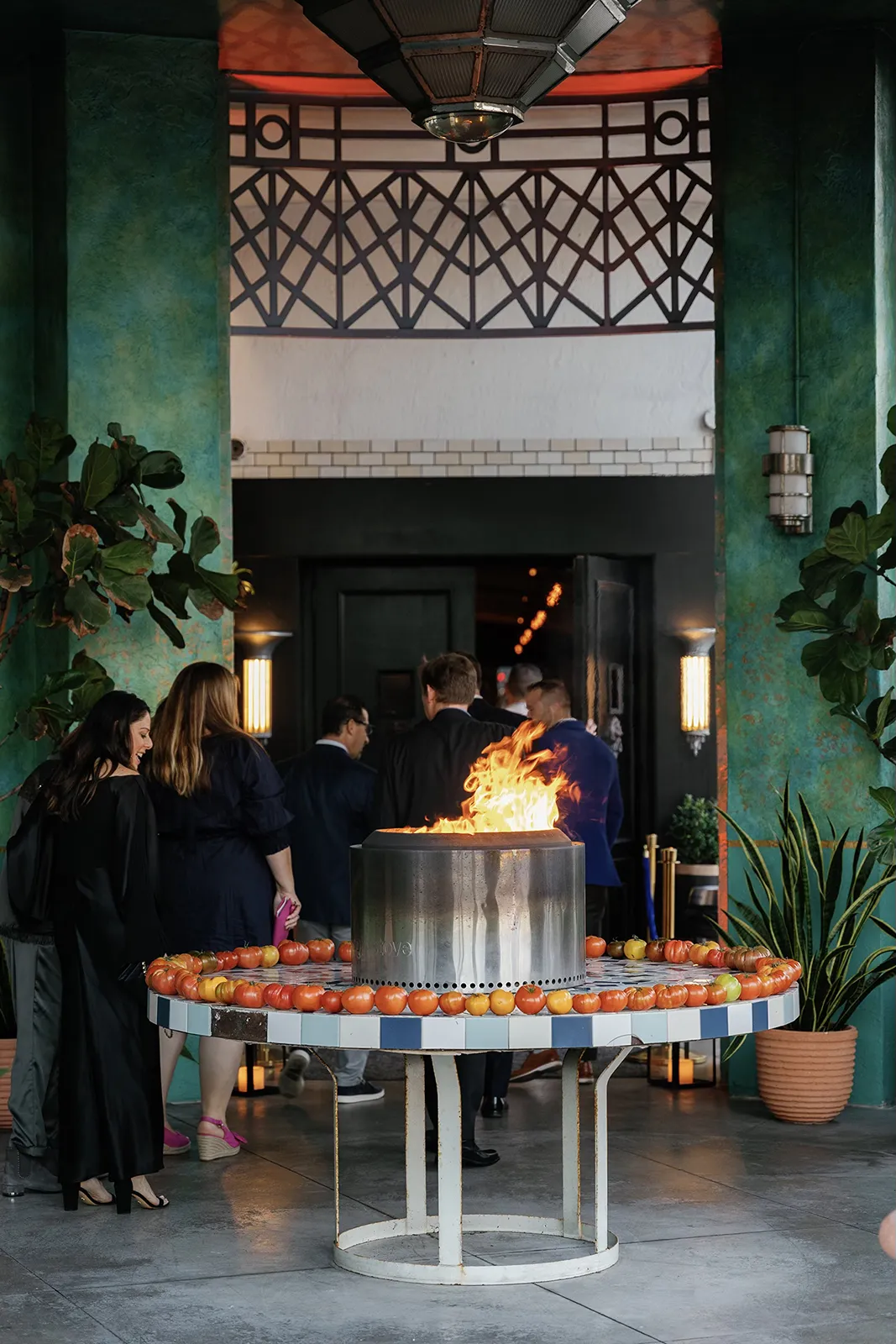 Guests arriving and gathering near a dramatic fire entrance feature before the rehearsal dinner begins