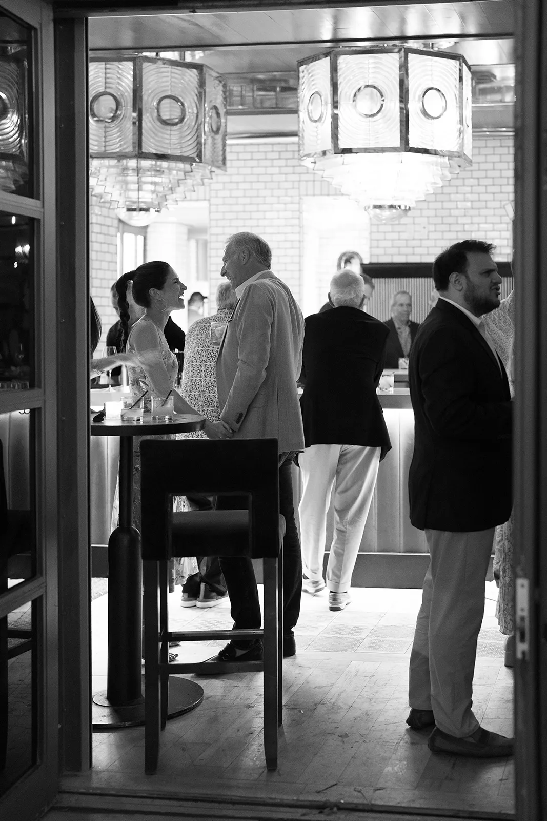 Wedding guests chatting and laughing together during cocktail hour at the rehearsal dinner
