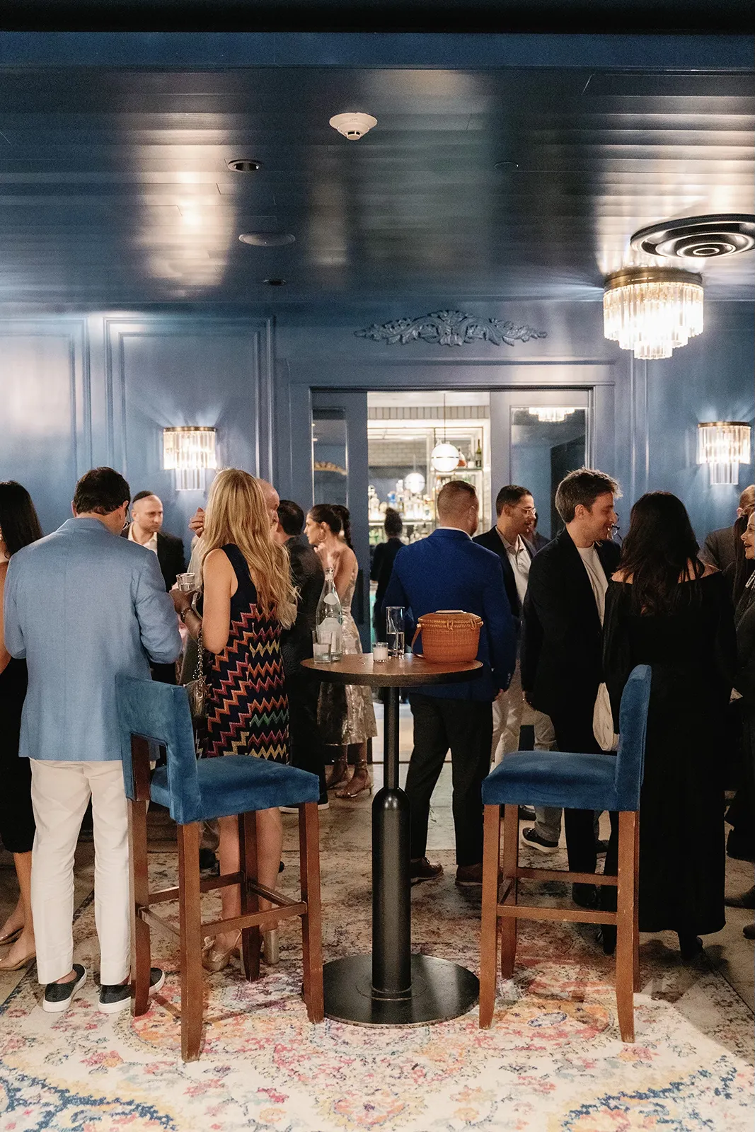 Guests mingling and socializing around cocktail tables before the rehearsal dinner