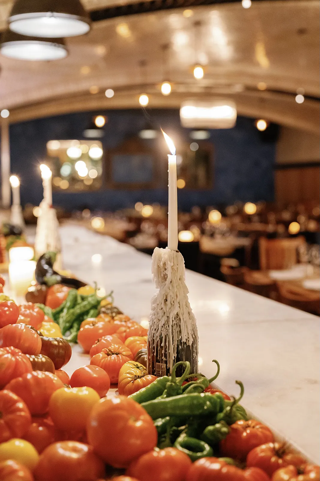 Candlelit table centerpiece featuring fresh vegetables arranged along the dinner table