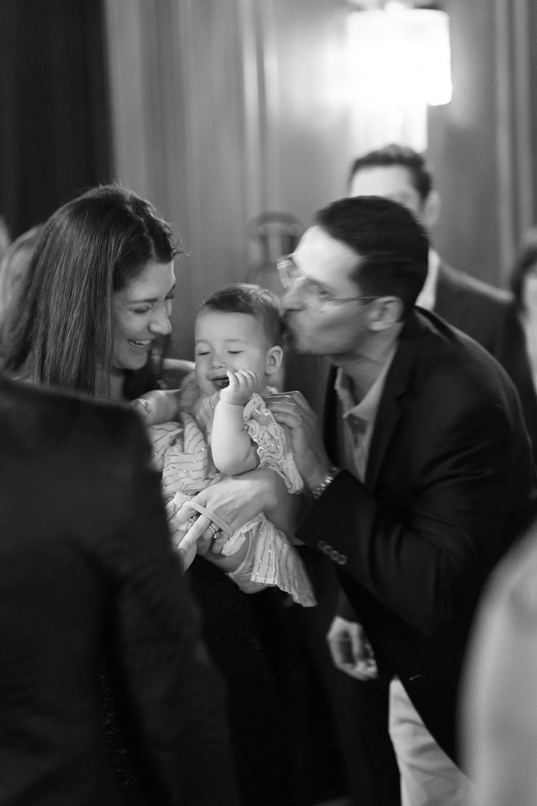 Parents sharing a joyful moment while holding their baby during the rehearsal dinner