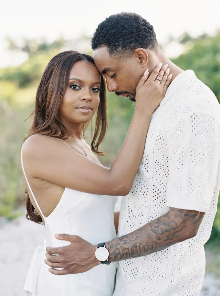 bride holding her fiancé's face close to her face as she looks at the camera