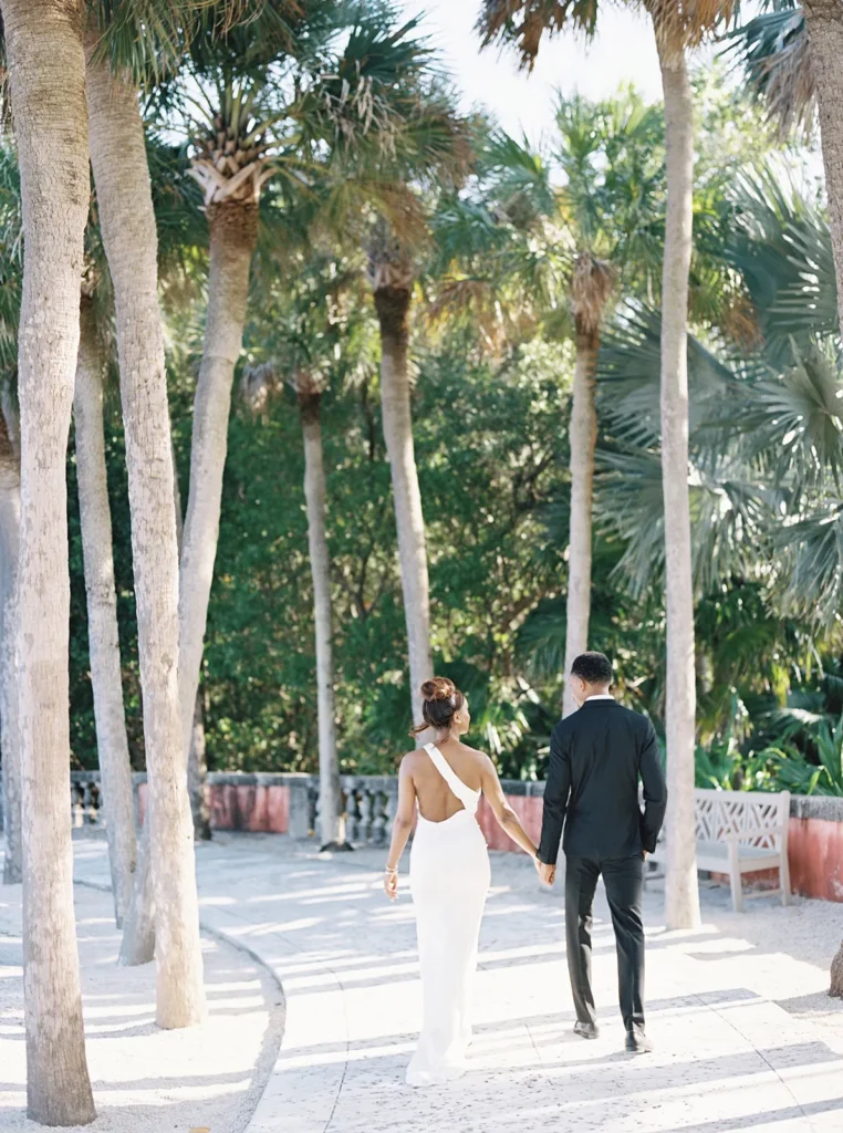 couple walking under various palm trees towards the tea house