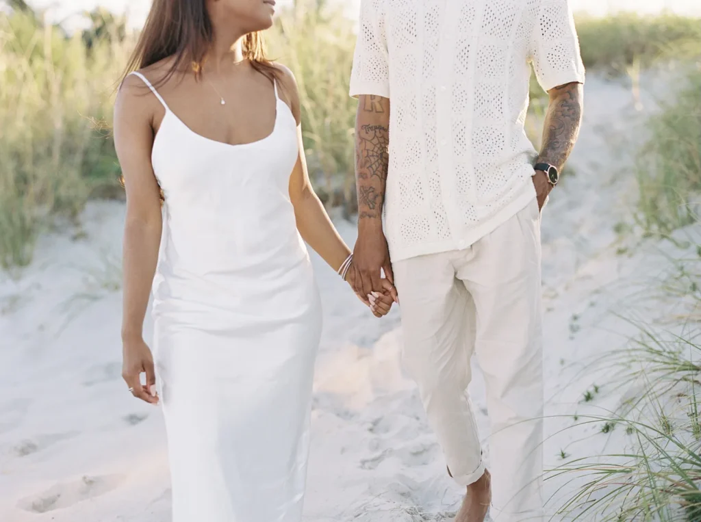 close up of bride's silk white dress and groom's light beige shirt and pants