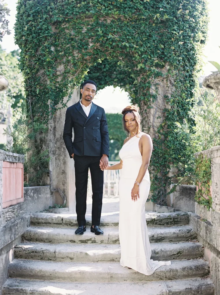 couple posing elegantly under an archway covered in a green vine
