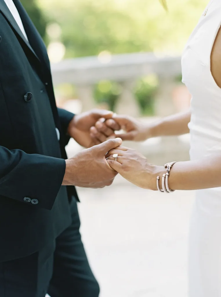 close up of couple holding hands while showcasing the engagement ring