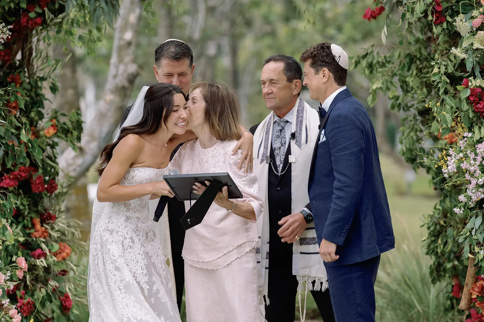 grandmother giving the bride a kiss under the chuppah