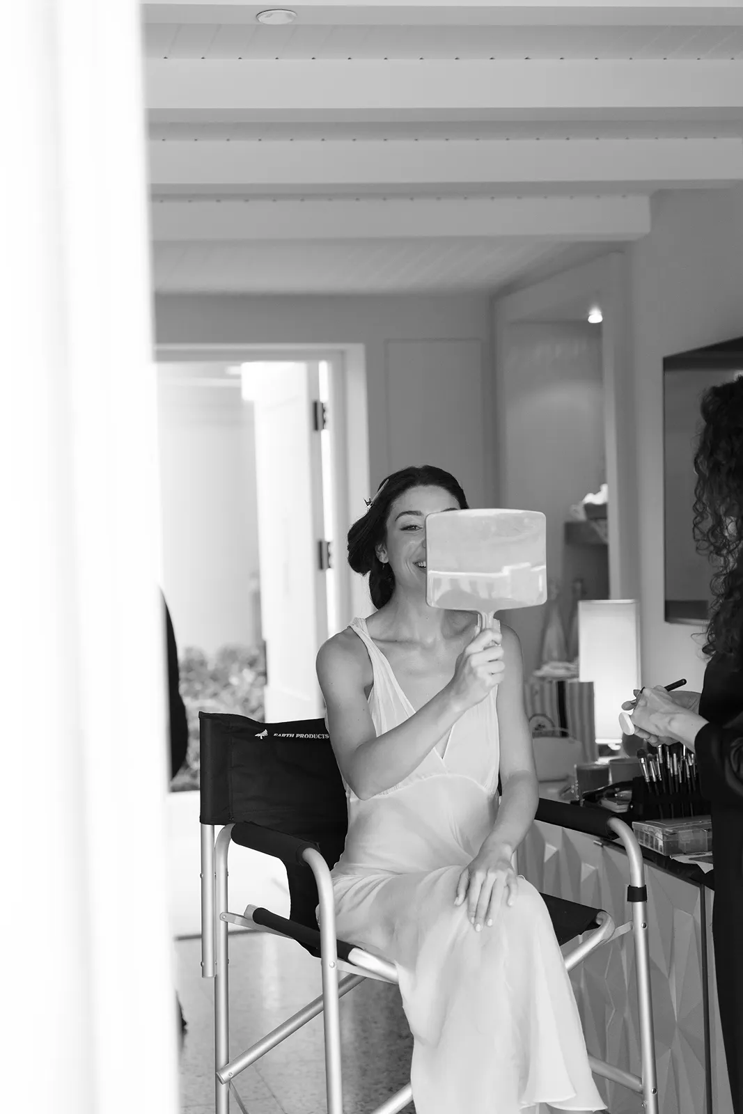 bride holding a mirror to check on her makeup while she gets ready