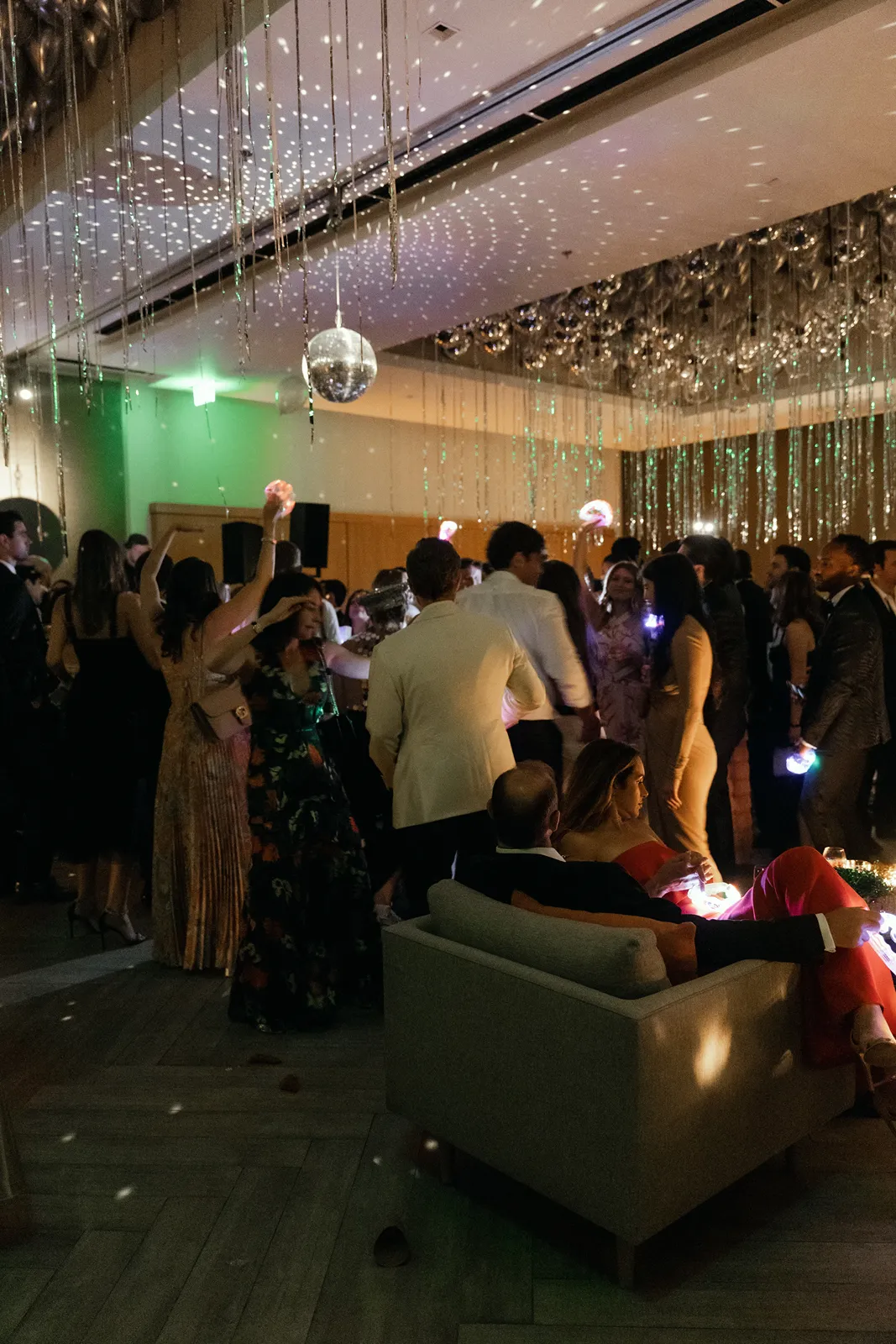 Wedding guests dance beneath hanging metallic streamers and disco ball lighting during an energetic after-party at Montage Healdsburg