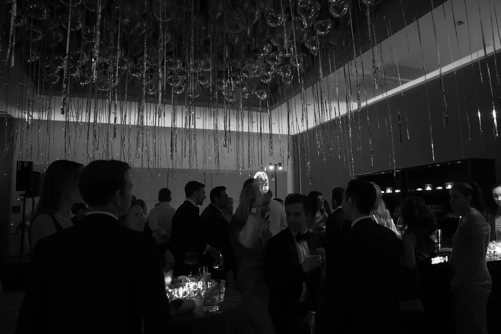 black and white of guests gathered around the bar