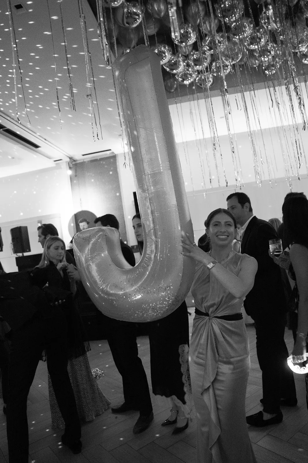 Wedding guest holding oversized letter balloon during the after party