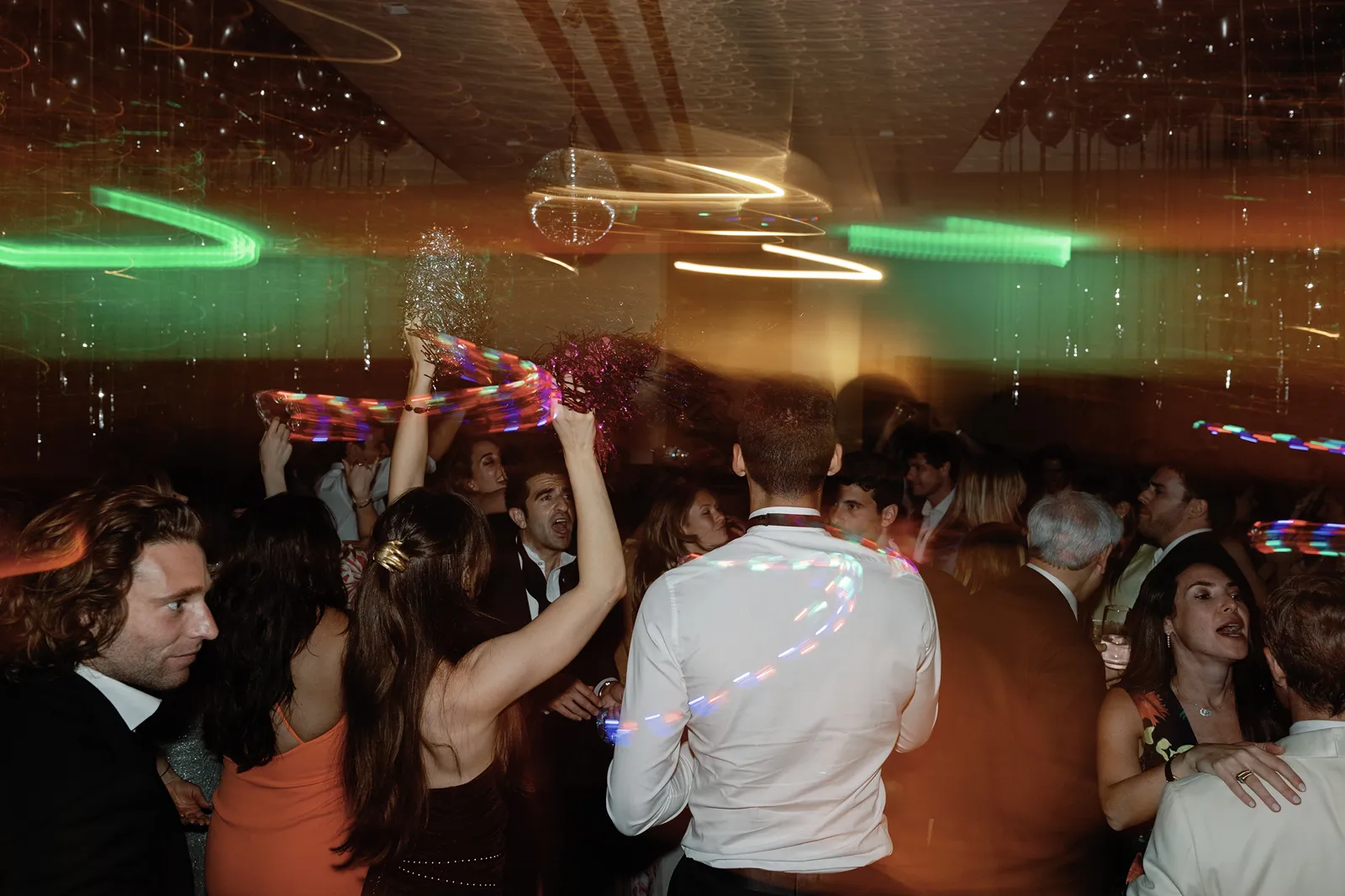 High-energy dance floor with guests waving light-up props at a Montage Healdsburg wedding after party