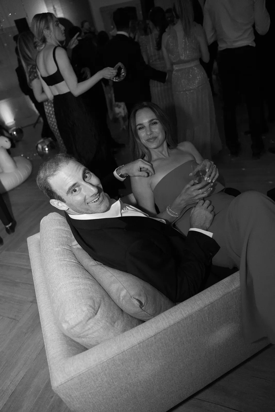 Wedding guests relaxing on a lounge couch during the evening reception and after party