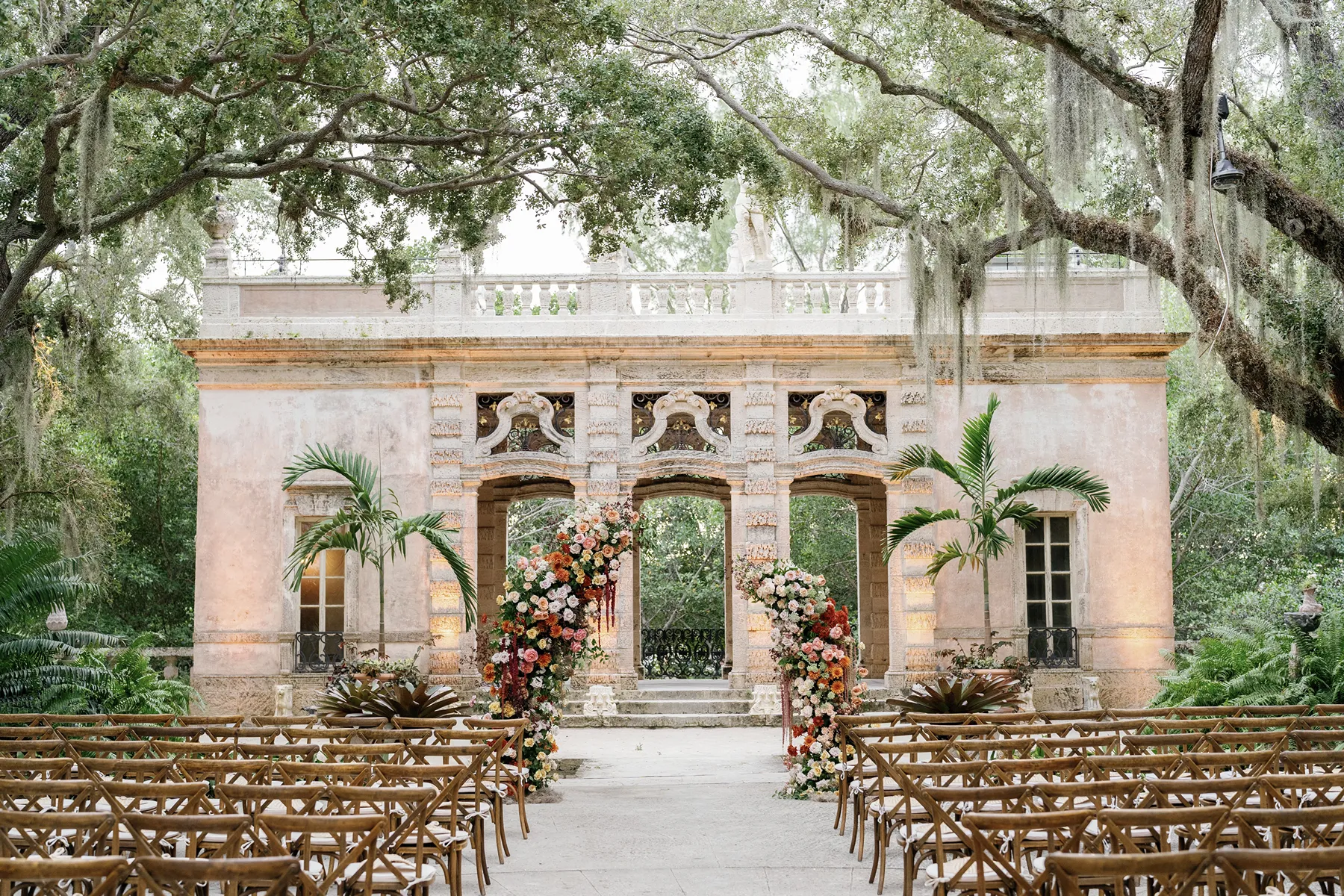 Elegant wedding ceremony setup at Vizcaya Museum & Gardens in Miami with floral arches
