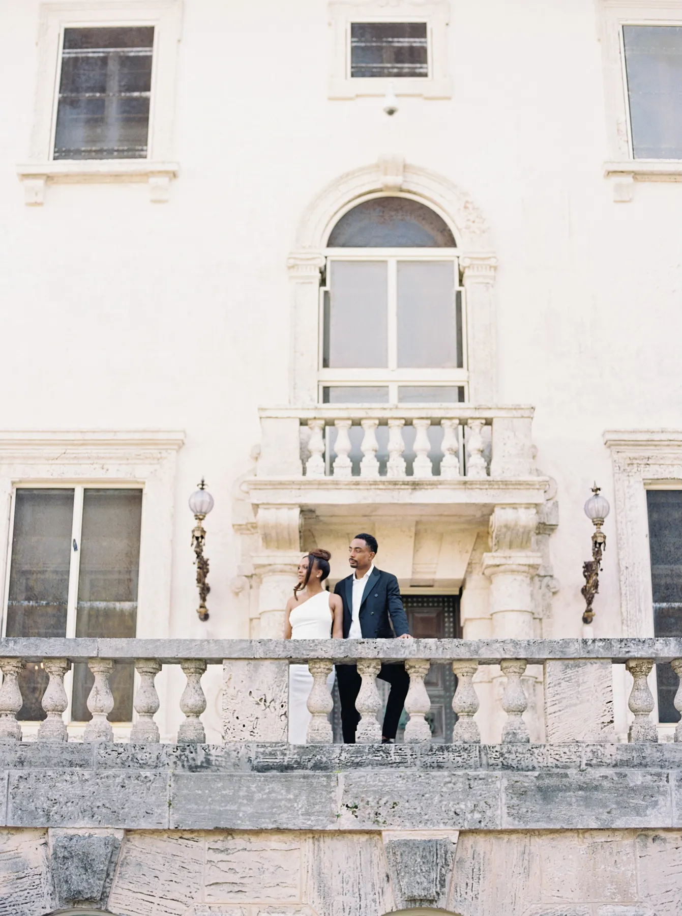 Bride and groom standing on a stone balcony at Vizcaya Museum & Gardens in Miami