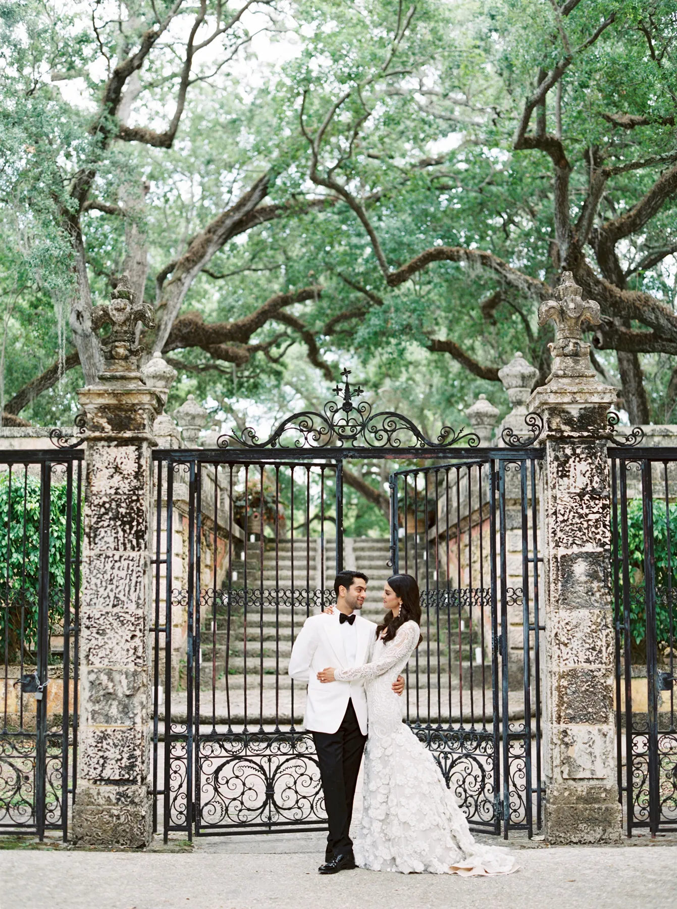 Bride and groom posing in front of ornate garden gates at Vizcaya Museum & Gardens